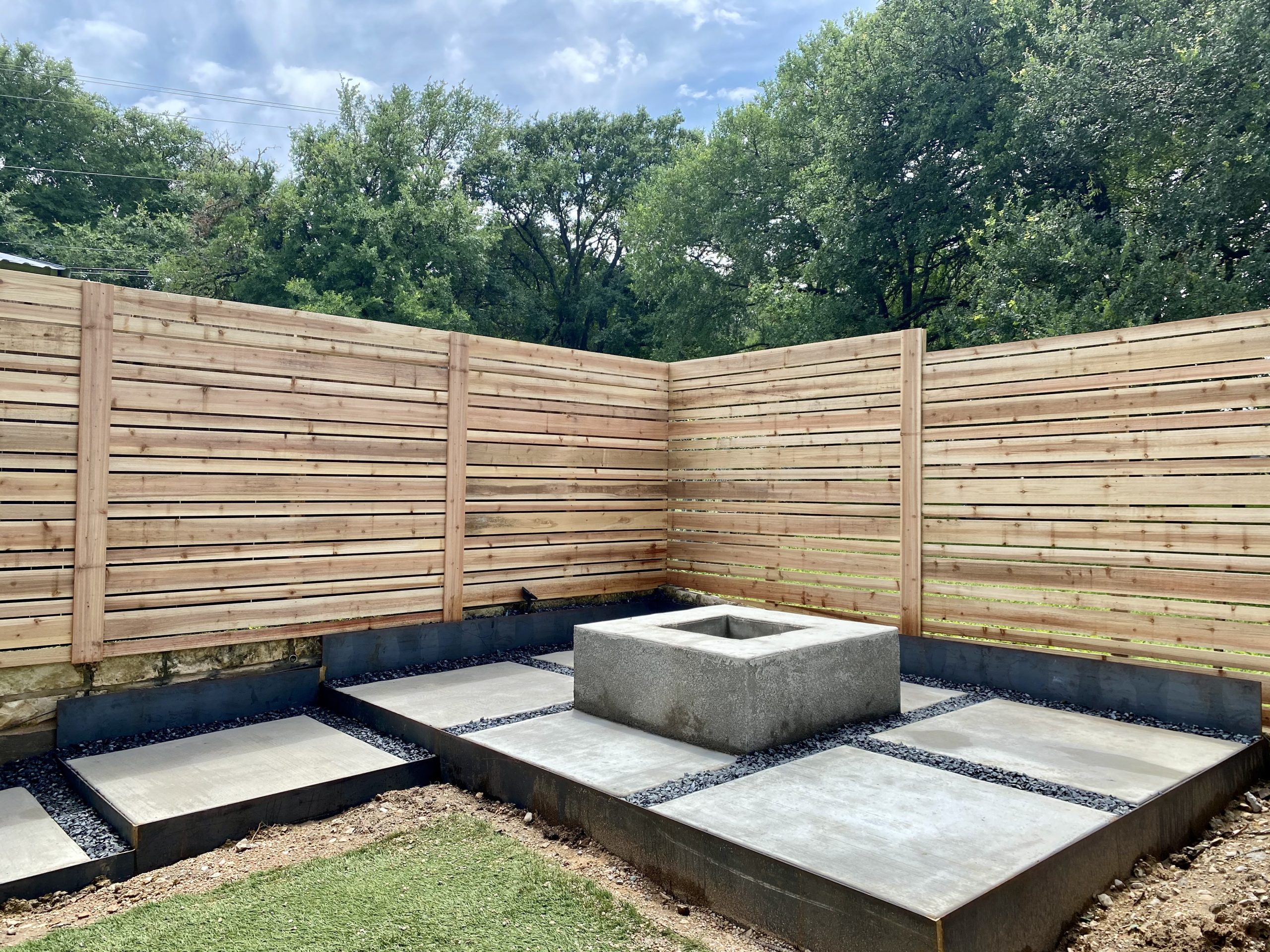 Custom limestone fire pit with curved seating in an Austin backyard at dusk. Fire pit ideas for Austin backyards